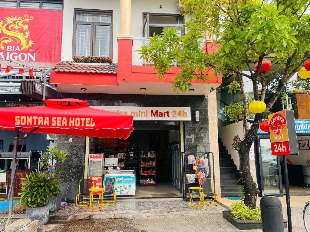 a store with a red umbrella and yellow tables and chairs at Sontra Sea Hotel in Danang
