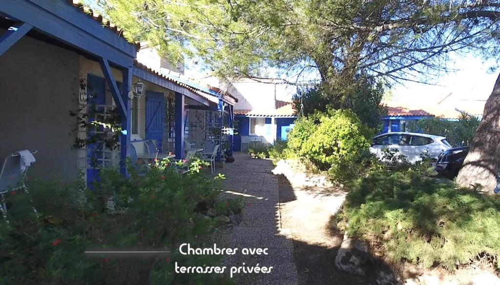 a sidewalk next to a house with a tree at Hotel Des 4 Vents "Esprit Camargue" Parking Privé securisé in Aigues-Mortes