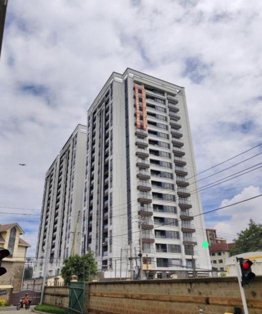 a tall white building on a city street at Kalm apartment- Luxury Living with a Gym, Heated Pool & Stunning Views in Nairobi