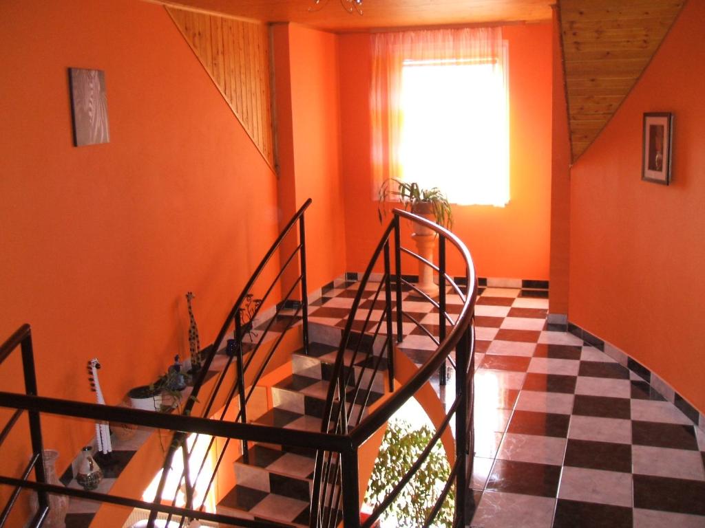 デブレツェンにあるTó Vendégházのオレンジ色の壁とチェッカーフロアの客室の階段