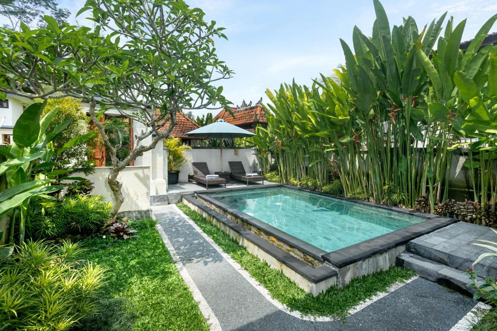 una piscina en un jardín con plantas en The Sakara Ubud Villas by GenuineHost, en Tegalalang