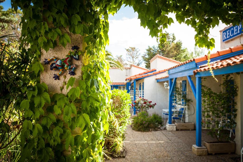 eine Wand mit grünem Efeu neben einem Gebäude in der Unterkunft Hotel Des 4 Vents "Esprit Camargue" Parking Privé securisé in Aigues-Mortes