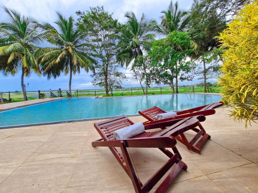 a pair of lounge chairs next to a swimming pool at Flamingo Lake Resort Tissamaharama in Modakandiya