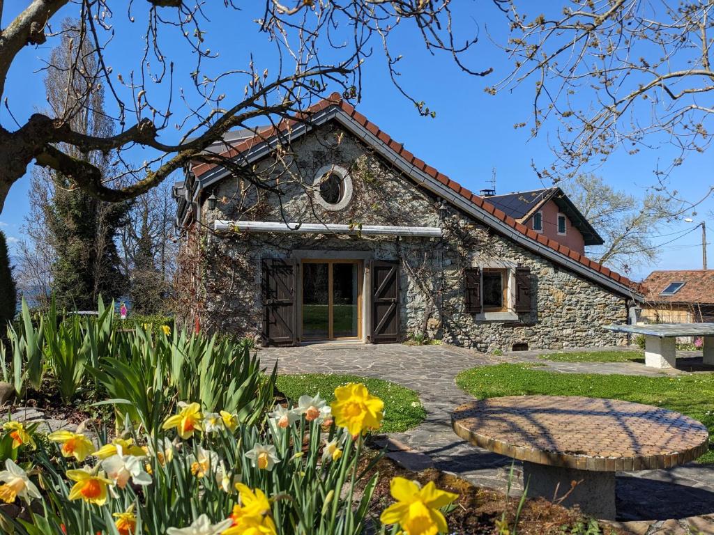 a stone house with flowers in front of it at Maison de charme au bord du lac Léman in Anthy