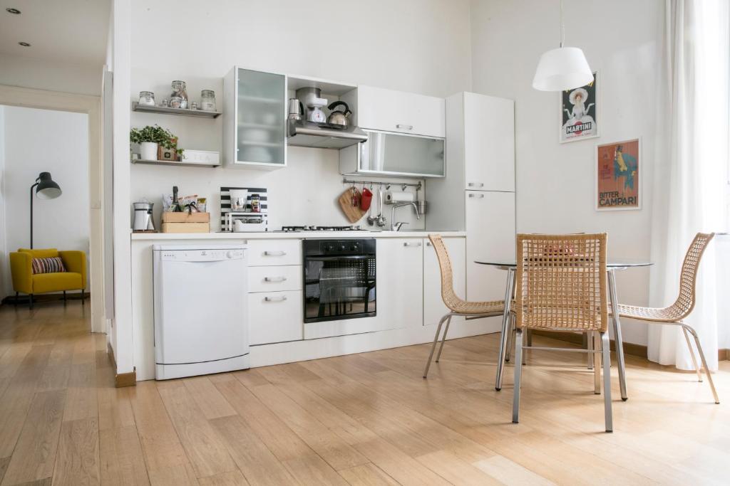 ミラノにあるLovely Sempione Apartmentの白いキャビネット、テーブルと椅子付きのキッチンが備わります。