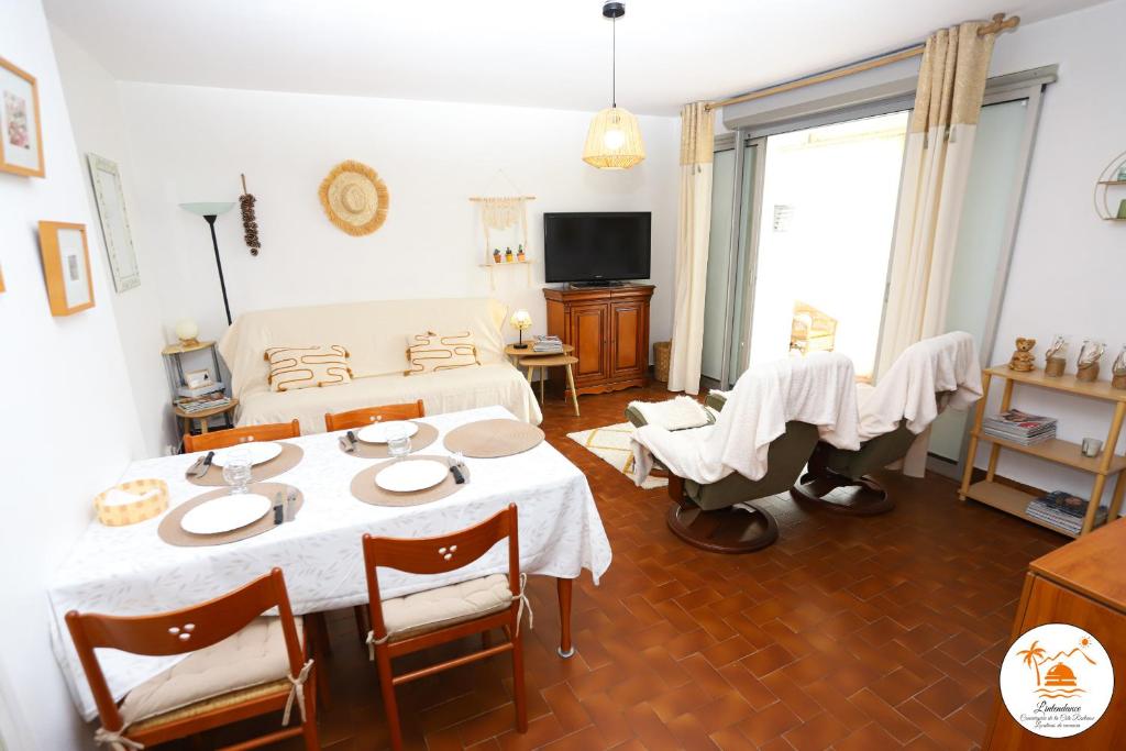 un salon avec une table, des chaises et une télévision dans l'établissement St Cyprien Appartement a 2 pas du port et de la plage, à Saint-Cyprien