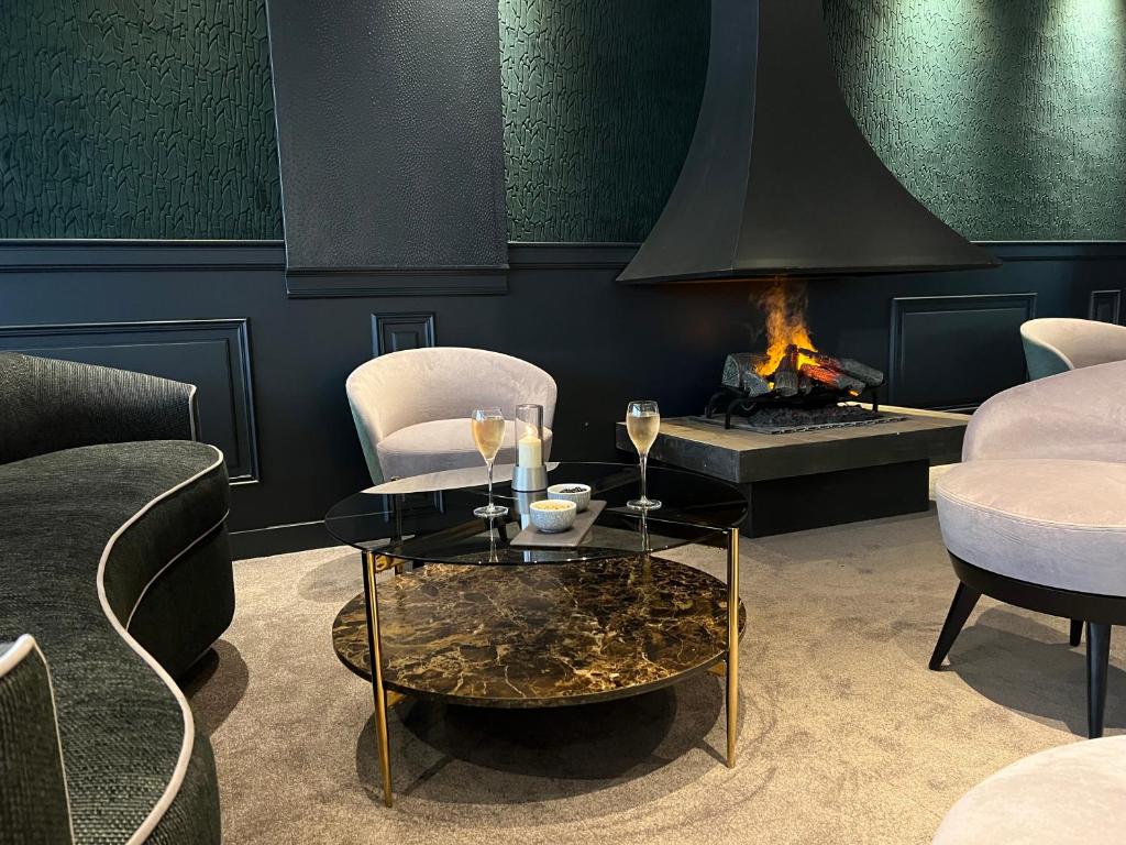 a room with two chairs and a table and a fireplace at Le Trophée Boutique Hôtel Spa- La Loggia Appart'hôtel in Deauville