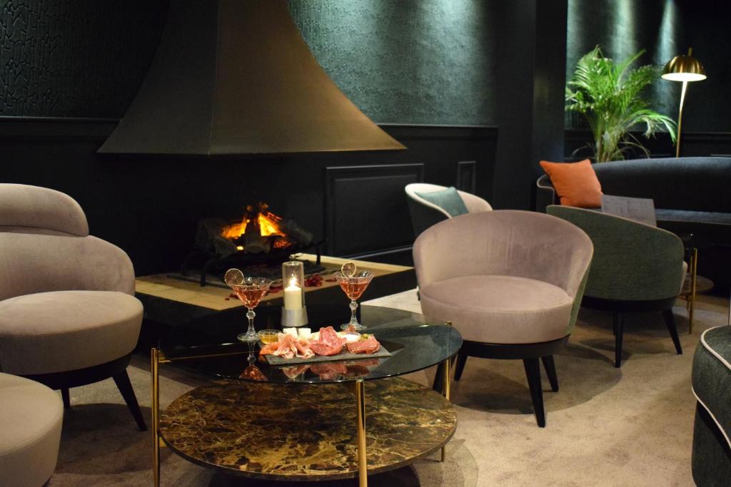 a room with chairs and a table and a fireplace at Le Trophée Boutique Hôtel Spa- La Loggia Appart'hôtel in Deauville