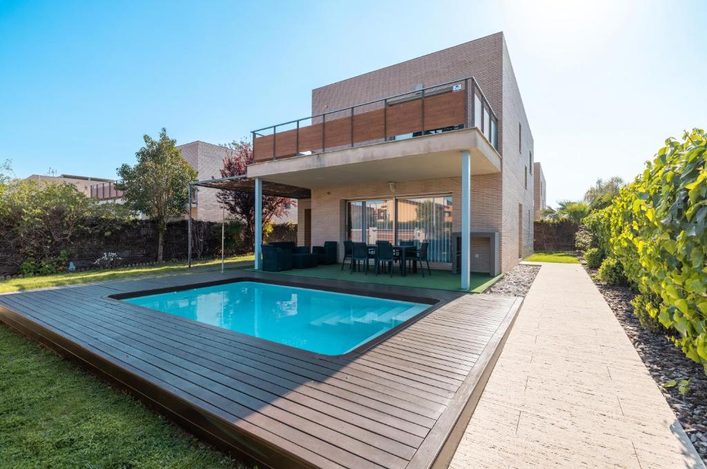 a house with a swimming pool on a wooden deck at Villa Vidalet solo familias in Cambrils