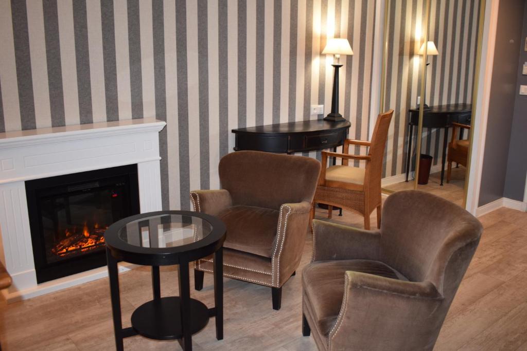 a living room with a fireplace and chairs and a table at Le Trophée Boutique Hôtel Spa- La Loggia Appart'hôtel in Deauville