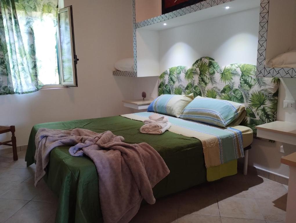 a bedroom with a bed with a green blanket on it at agriturismo heaven in Capo Vaticano