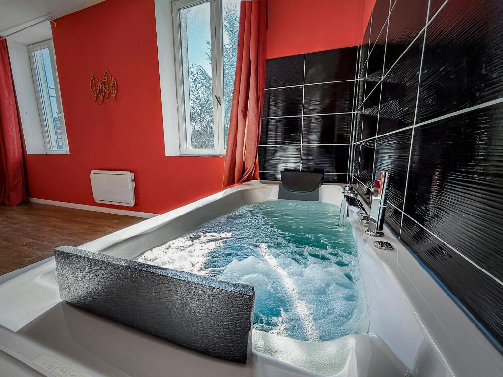 a jacuzzi tub in a room with red walls at Studio Chic N2 avec Jacuzzi in Roubaix