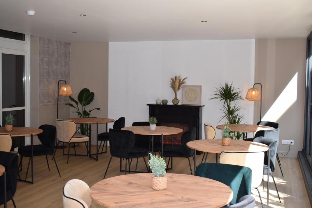 a room with several tables and chairs and a room with plants at Le Trophée Boutique Hôtel Spa- La Loggia Appart'hôtel in Deauville