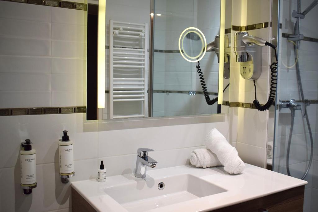 a bathroom with a sink and a mirror at Le Trophée Boutique Hôtel Spa- La Loggia Appart'hôtel in Deauville