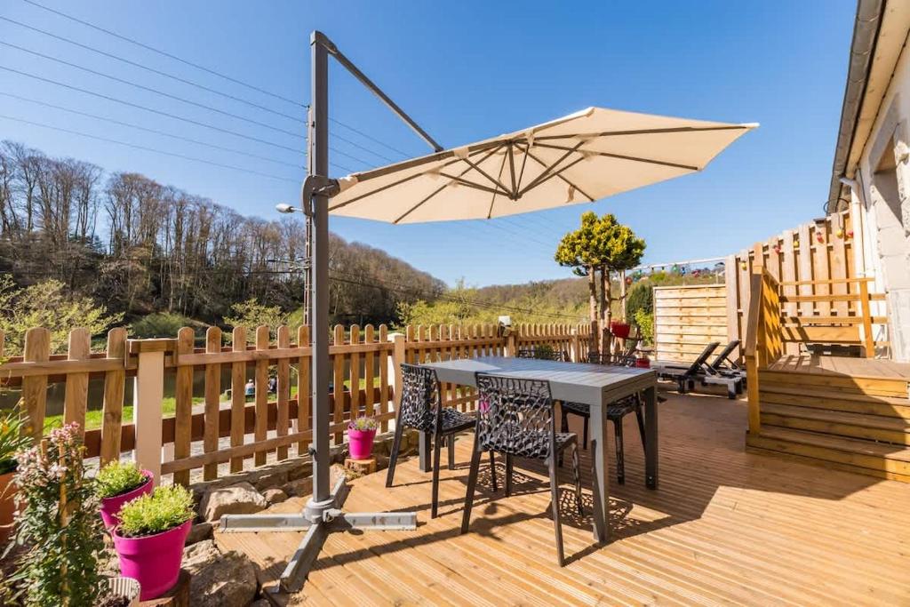 a table and chairs under an umbrella on a deck at Terrasse charme & nature en coeur de Lannion in Lannion