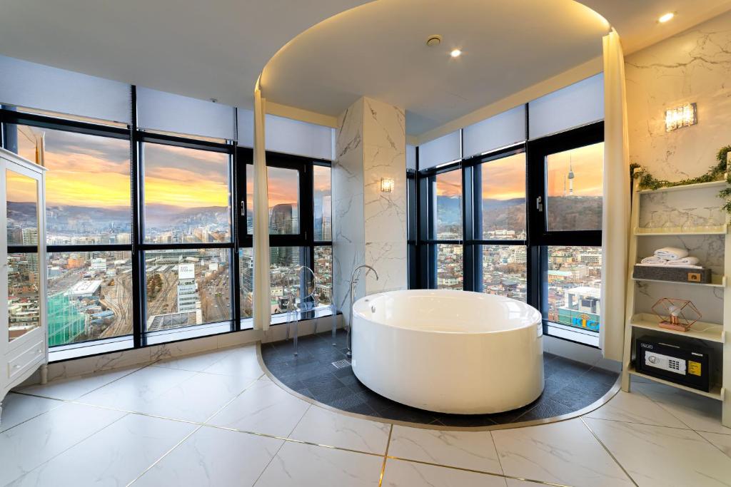 - une grande salle de bains avec une baignoire en face des fenêtres dans l'établissement Hotel The Designers Seoul Station, à Séoul