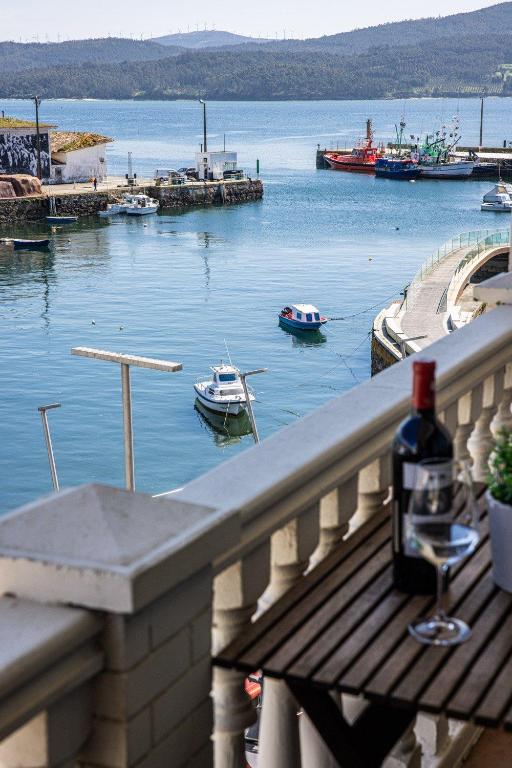 a bottle of wine sitting on a balcony overlooking a harbor at Apartamentos Arnela in Camariñas