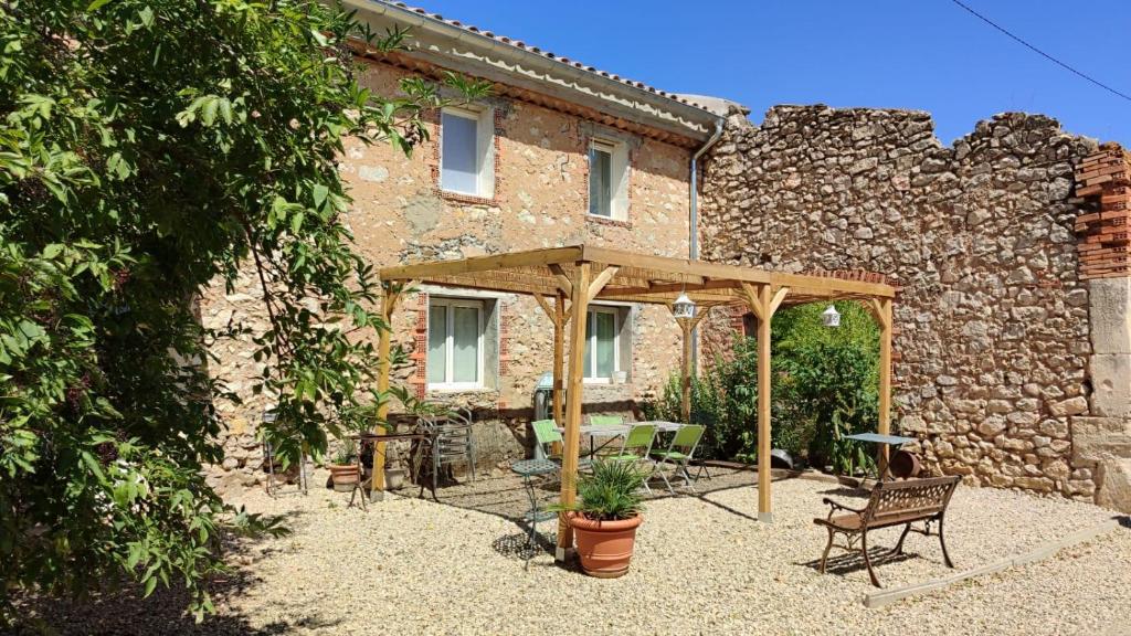 un patio devant un bâtiment en briques avec un auvent en bois dans l'établissement Le gîte du moulin, à Thézan-des-Corbières