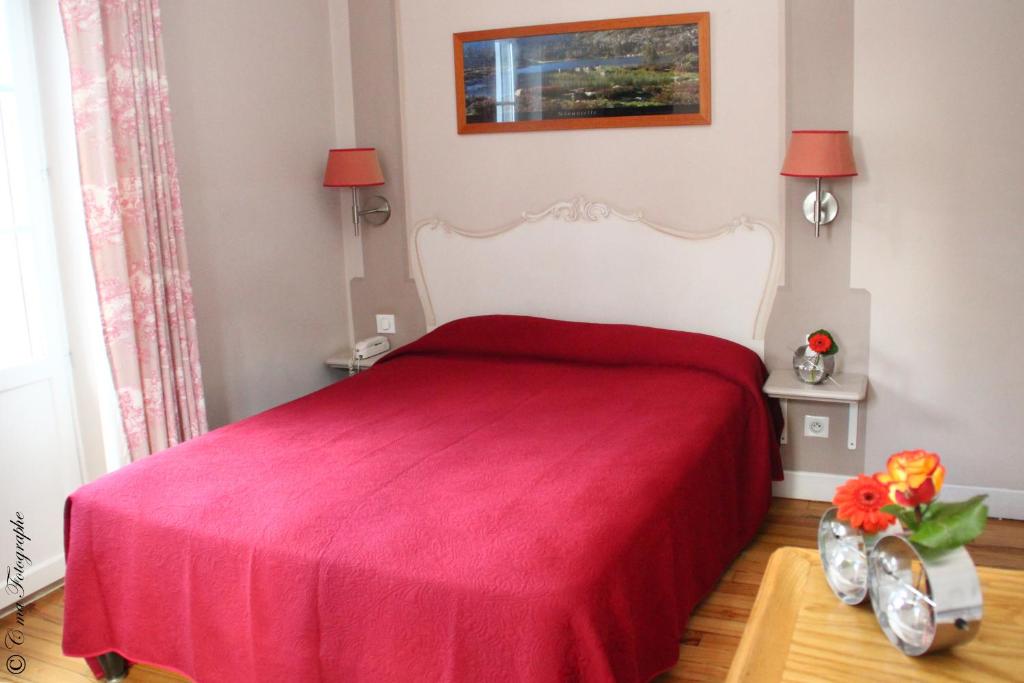 a bedroom with a bed with a red blanket at Hôtel Majestic in Lourdes