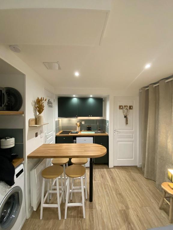 une cuisine avec une table et des tabourets dans une pièce dans l'établissement Le Nid'Ophé Studio Cosy - Proche Disneyland Paris, à Mareuil-lès-Meaux