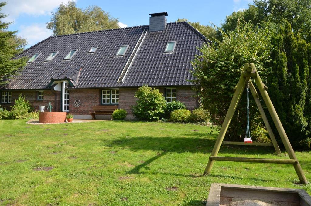 a large house with a yard with a swing at Landhaus Birkenhof in Varel