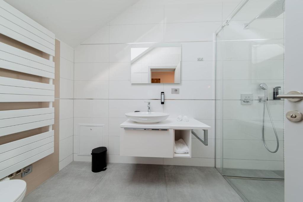 a white bathroom with a sink and a shower at Carolina Luxury Stay in Rogašovci