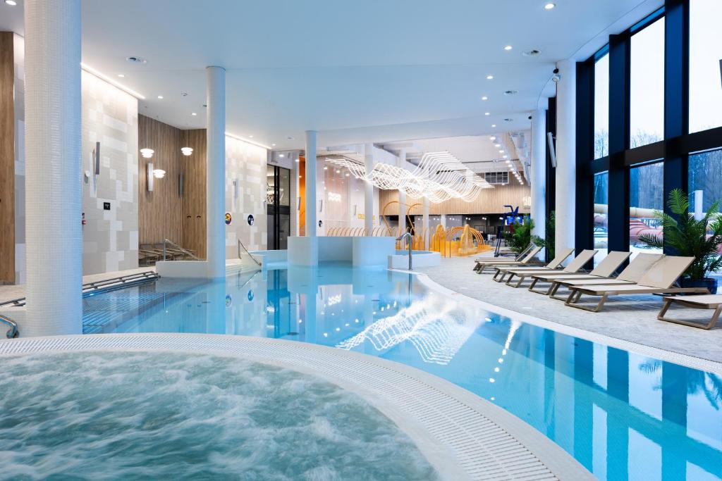 ein großer Pool in einem Hotel mit Stühlen in der Unterkunft Mercure Szczyrk Resort in Szczyrk