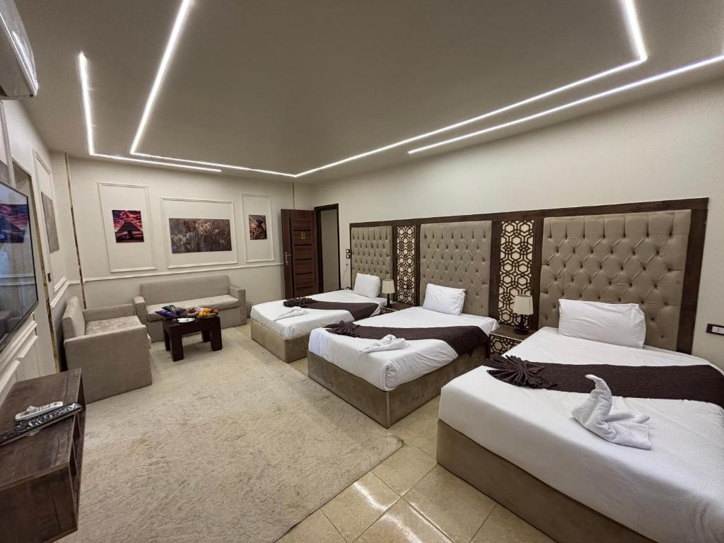 una habitación de hotel con tres camas y un sofá en Master pyramids Hotel, en El Cairo