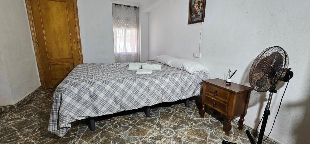 a bedroom with a bed with a fan and a table at Habitaciones en Chalet 1º linea de playa in Cullera
