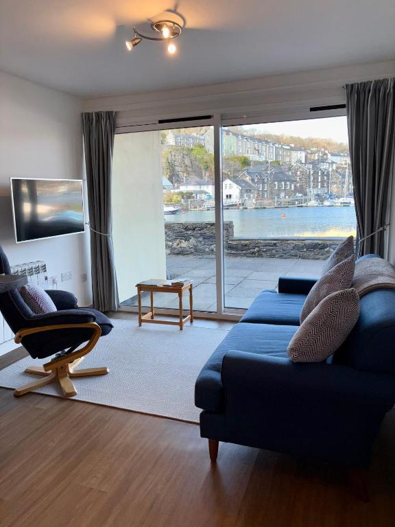 a living room with a blue couch and a large window at Georgina Portview- Pet Free-Allergy Friendly in Porthmadog