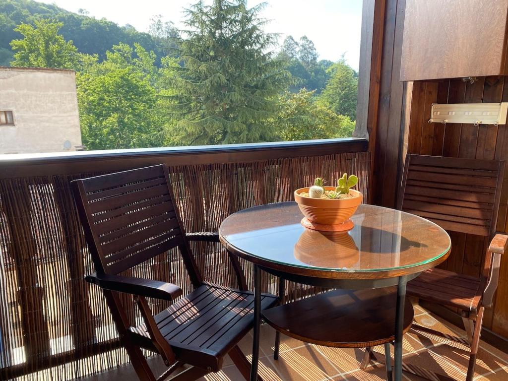 a table and chairs on a balcony with a window at Balcón del atardecer in Cangas de Onís