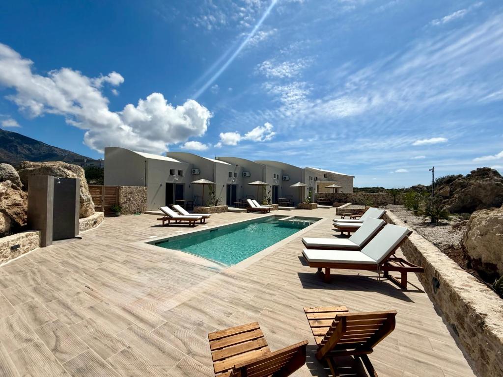 a swimming pool with lounge chairs next to a house at Cove Elafonisi Apartments in Elafonisi