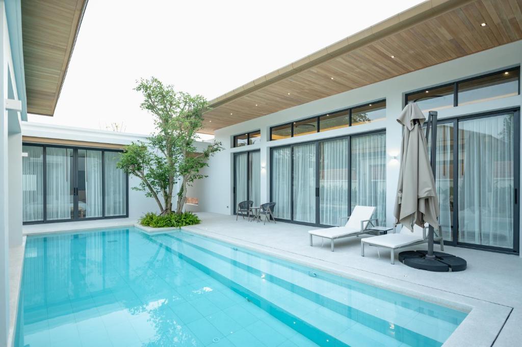 a swimming pool with two chairs and a building at Mouana Breeze Mai Khao 4-bedroom Pool Villa 9918 in Mai Khao Beach