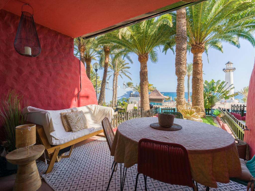 een terras met een tafel, een bank en palmbomen bij Blue Horizon Retreat in Playa del Aguila