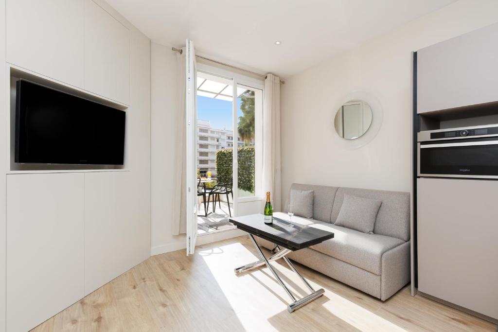 un salon avec un canapé et une télévision dans l'établissement Palais Miramar YourHostHelper, à Cannes
