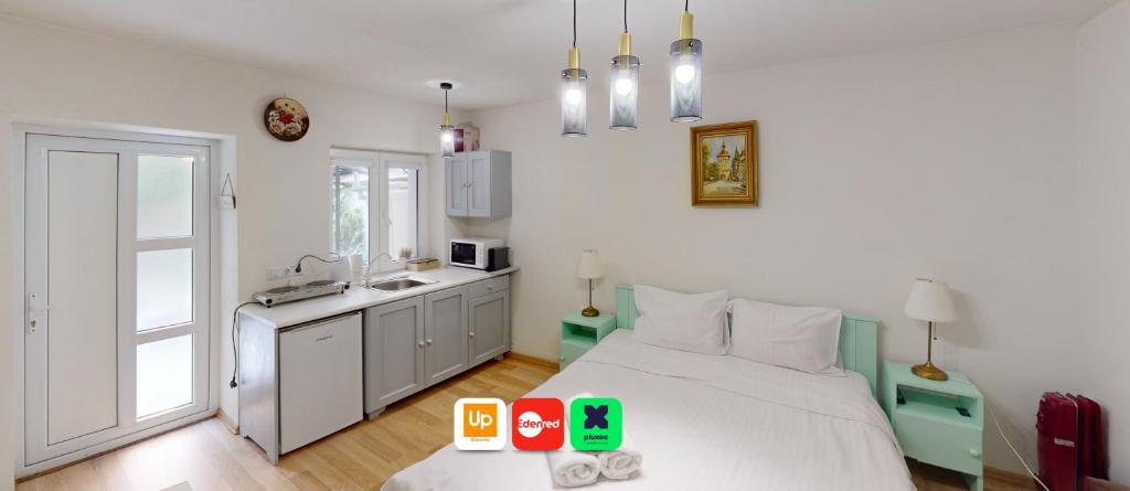 a bedroom with a white bed and a kitchen at Tischler Studio VRT in Sibiu