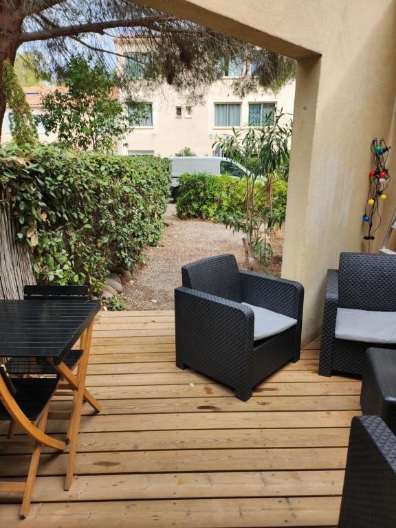 une terrasse en bois avec 2 chaises et une table. dans l'établissement CALVI STUDIO TERRASSE PLAGe, à Calvi