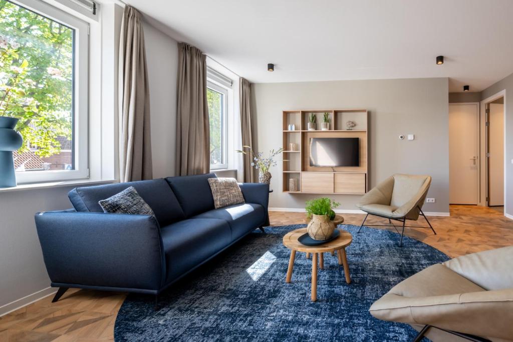 ein Wohnzimmer mit einem blauen Sofa und einem Tisch in der Unterkunft Residence Noordstaete vakantieappartement Lepelaar in Burgh Haamstede