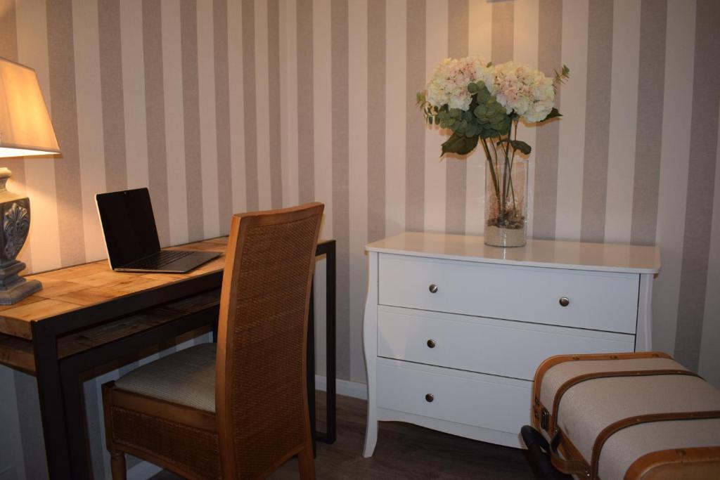 a bedroom with a desk with a laptop and a vase of flowers at Le Trophée Boutique Hôtel Spa- La Loggia Appart'hôtel in Deauville