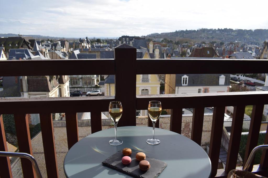 a table with two glasses of wine on a balcony at Le Trophée Boutique Hôtel Spa- La Loggia Appart'hôtel in Deauville