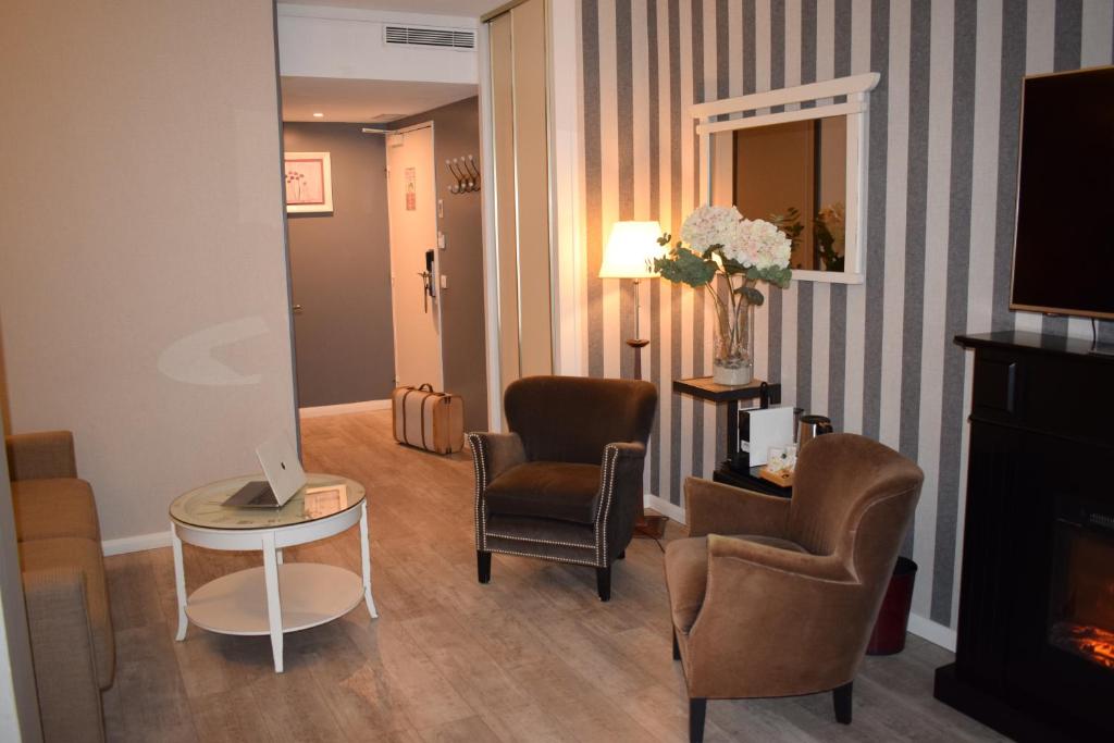 a living room with chairs and a table and a fireplace at Le Trophée Boutique Hôtel Spa- La Loggia Appart'hôtel in Deauville