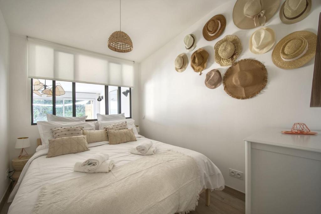 - une chambre blanche dotée d'un grand lit avec des chapeaux au mur dans l'établissement Le Mas Emeraude ~ Jardin ~ Parking ~ Climatisation, à Nîmes