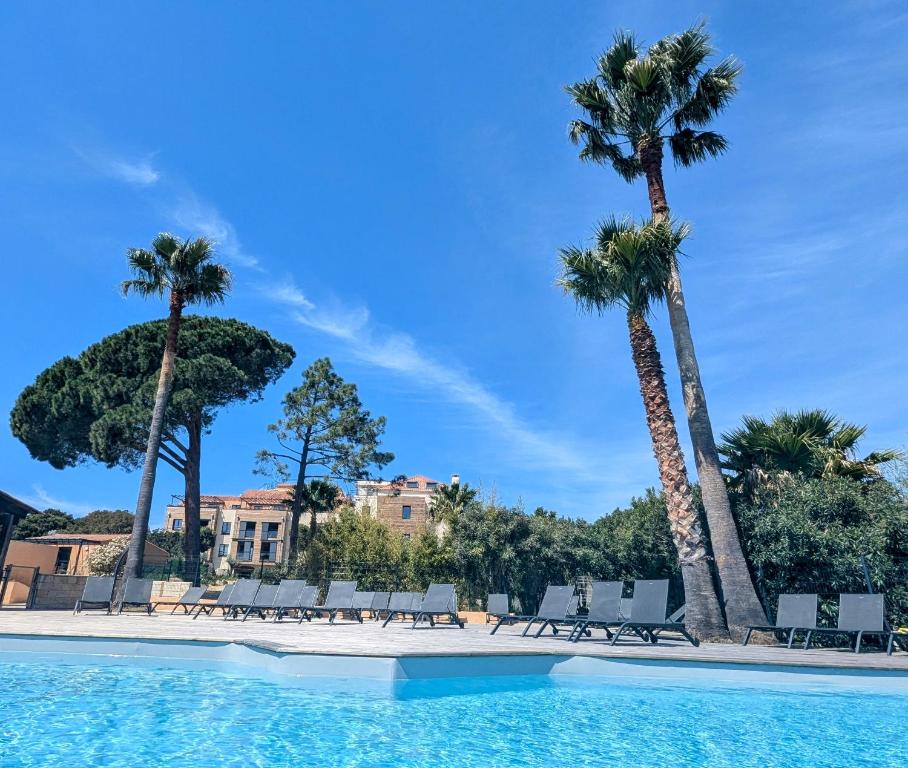 - une piscine bordée de palmiers et de chaises longues dans l'établissement Magnifique 70m2 avec patio terrasse en bord de mer, à Pianottoli-Caldarello