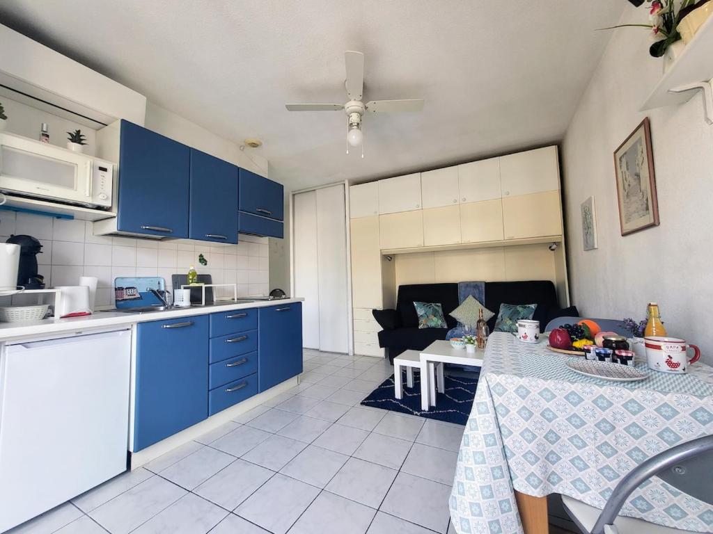 une cuisine avec des placards bleus, une table et un canapé dans l'établissement Valery Close to beach Prom des Anglais Ideal for 2 AC, à Nice