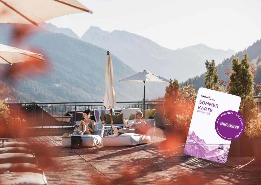 two people are sitting on the patio of a resort at Anthony's Life&Style Hotel in Sankt Anton am Arlberg
