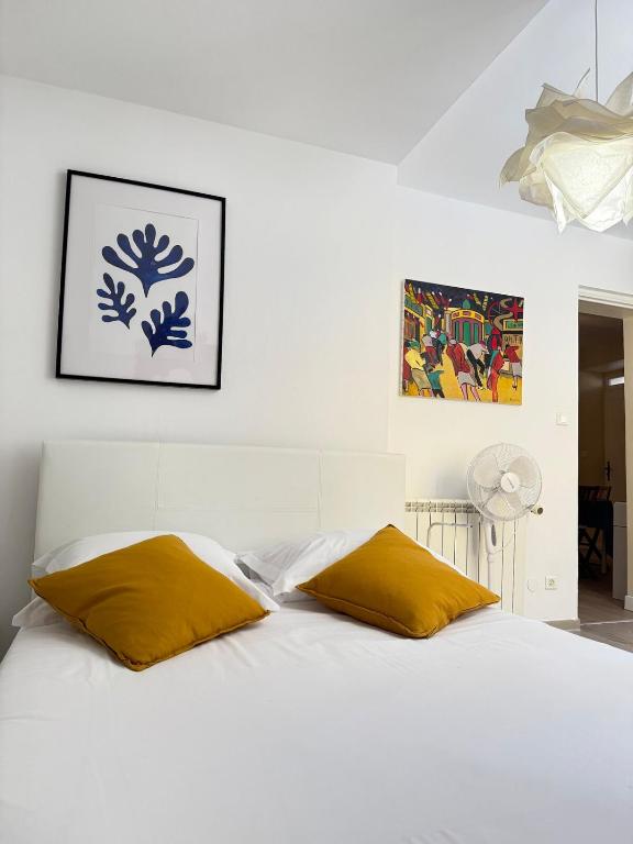 - une chambre avec un lit blanc et 2 oreillers jaunes dans l'établissement Le Favorin 1, à Arles