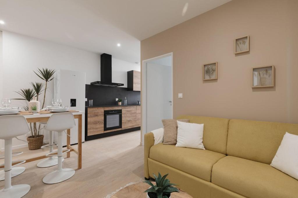 un salon avec un canapé jaune et une cuisine dans l'établissement OIQIA • Arthéa • Esquisse, à Périgueux