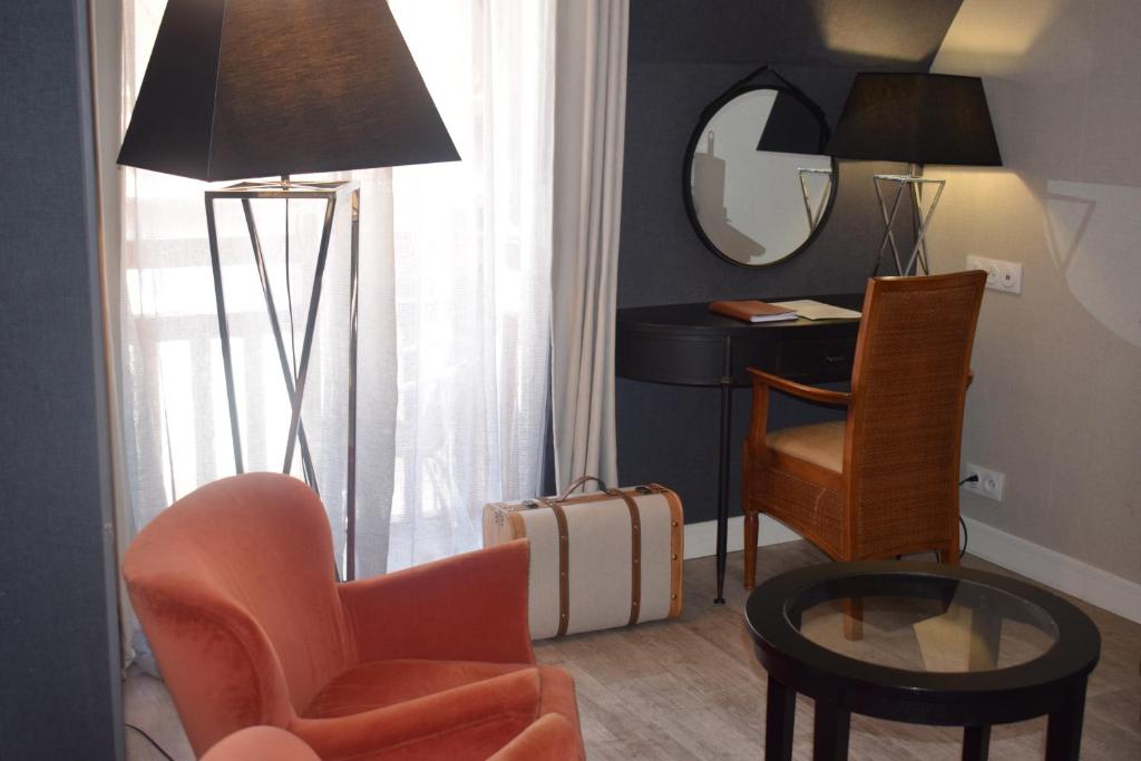 a living room with a chair and a table and a mirror at Le Trophée Boutique Hôtel Spa- La Loggia Appart'hôtel in Deauville