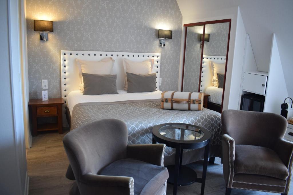 a hotel room with a bed and two chairs and a mirror at Le Trophée Boutique Hôtel Spa- La Loggia Appart'hôtel in Deauville