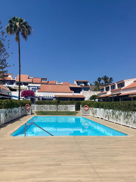 an empty swimming pool with a palm tree in the background at Relax Los veleros in Pasito Blanco